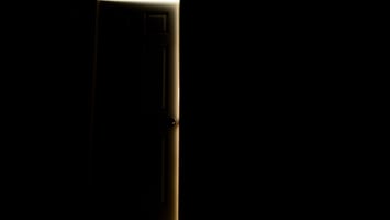 A door cracked open in darkness with warm light spilling through the edges, representing the 12 house parties of your birth chart astrology series by the earth siren