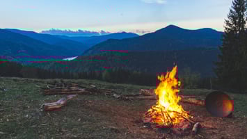 Campfire burning steadily on a quiet mountainside at dusk, reflecting Earth Siren astrology themes of fire sign energy and presence.
