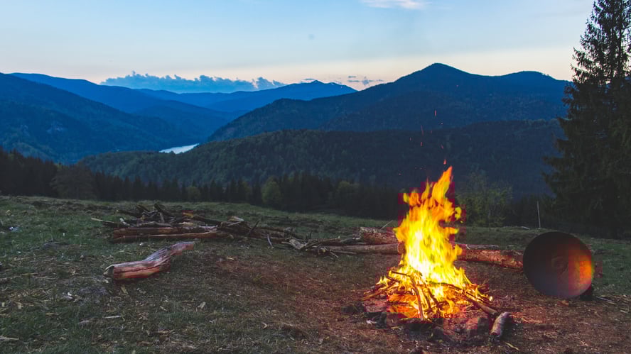 Campfire burning steadily on a quiet mountainside at dusk, reflecting Earth Siren astrology themes of fire sign energy and presence.