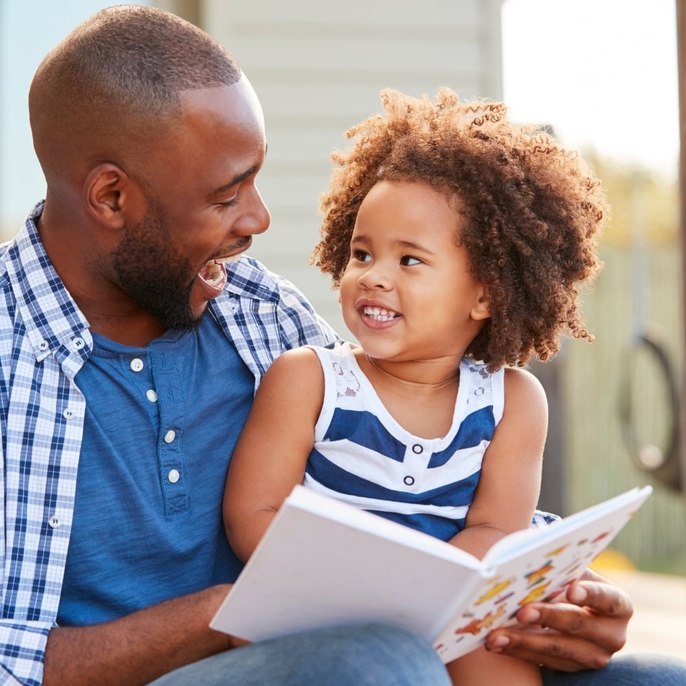 Parent reading with a child outdoors, symbolizing mindful parenting and understanding child development through astrology