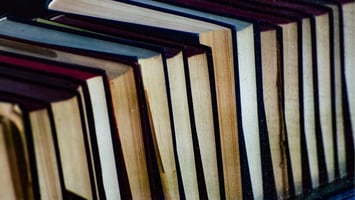 Stack of worn books representing reference knowledge and structured learning, aligned with birth chart interpretation and astrology terminology