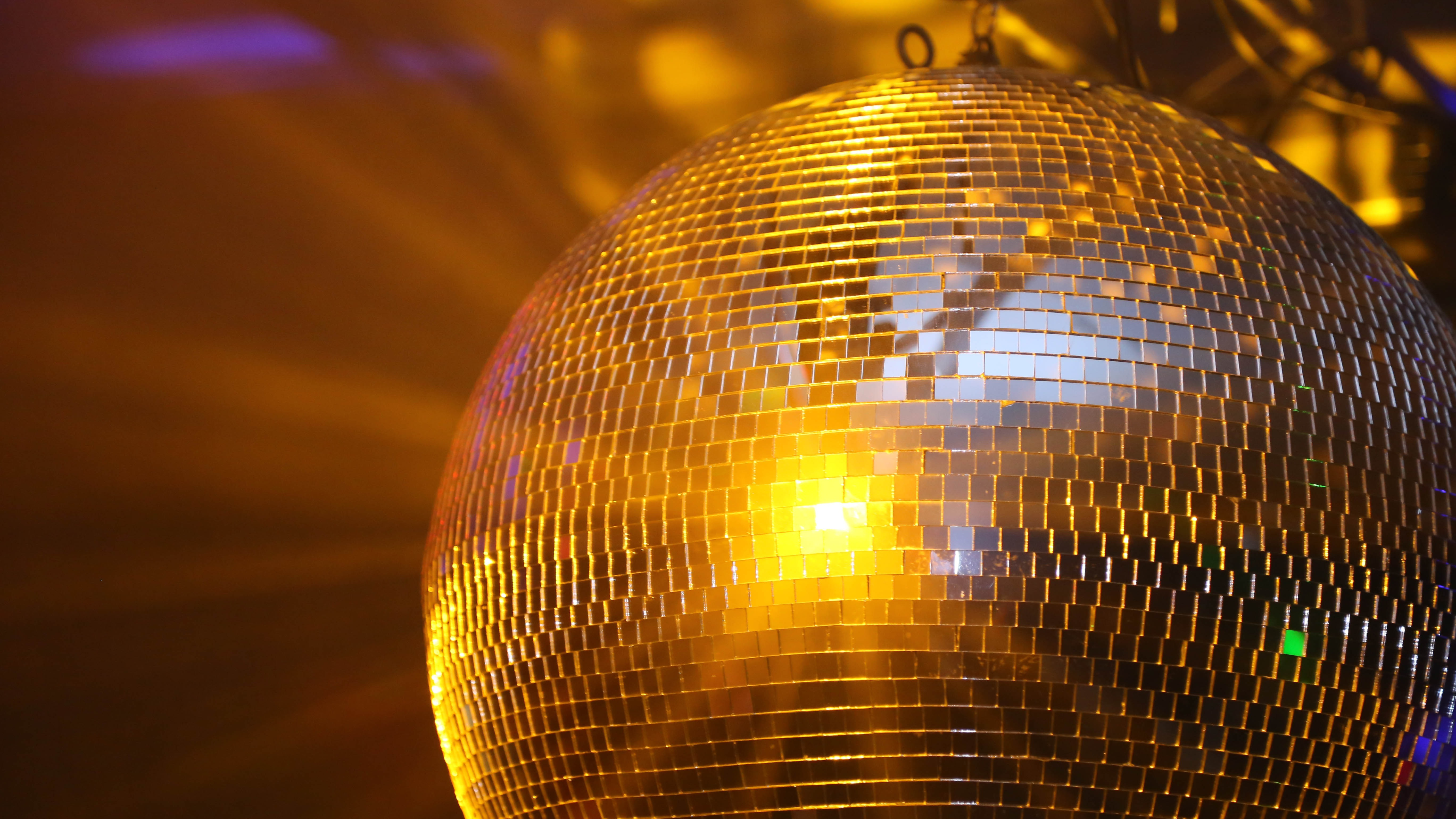 A gold disco ball glowing under warm party lighting at a 5th house astrology birthday celebration hosted by the Sun.png